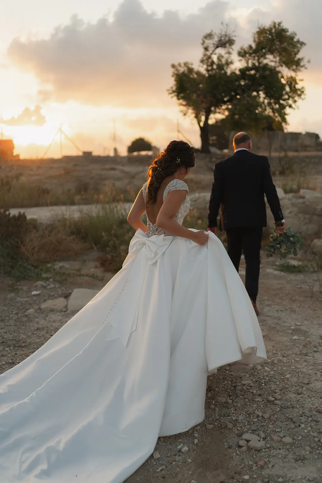 Bride and groom walking into a dramatic clouded sunset sky at Liopetro, Paphos, Cyprus