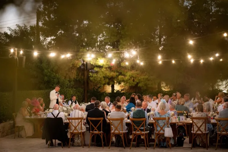 Wedding reception under festoon lights at dusk as the couple and guests gather at a Cyprus venue.