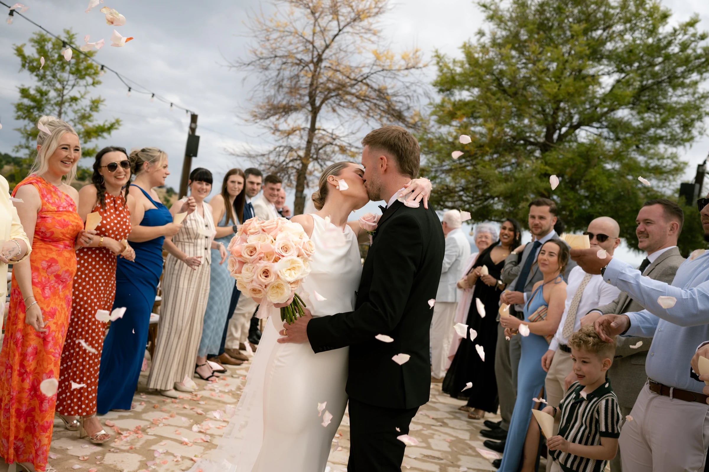 Confetti kiss as the couple exit their ceremony surrounded by laughing guests at Liopetro, Paphos, Cyprus.