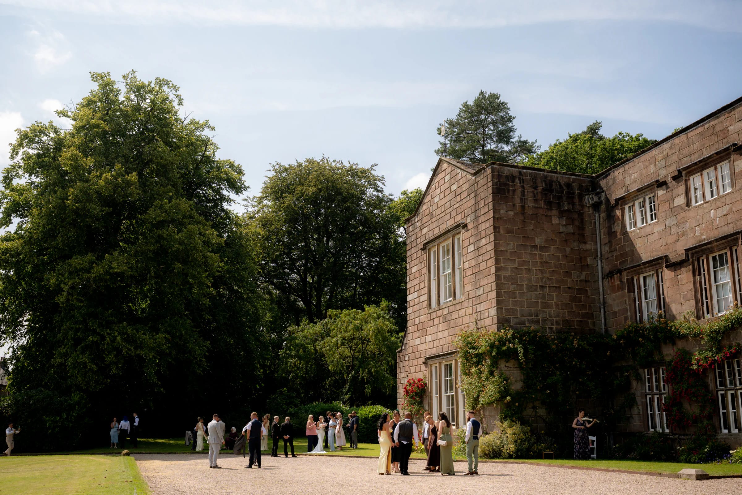 Guests gathering on the lawn beside Browsholme Hall after Josh and Ellie's outdoor wedding ceremony in Lancashire.