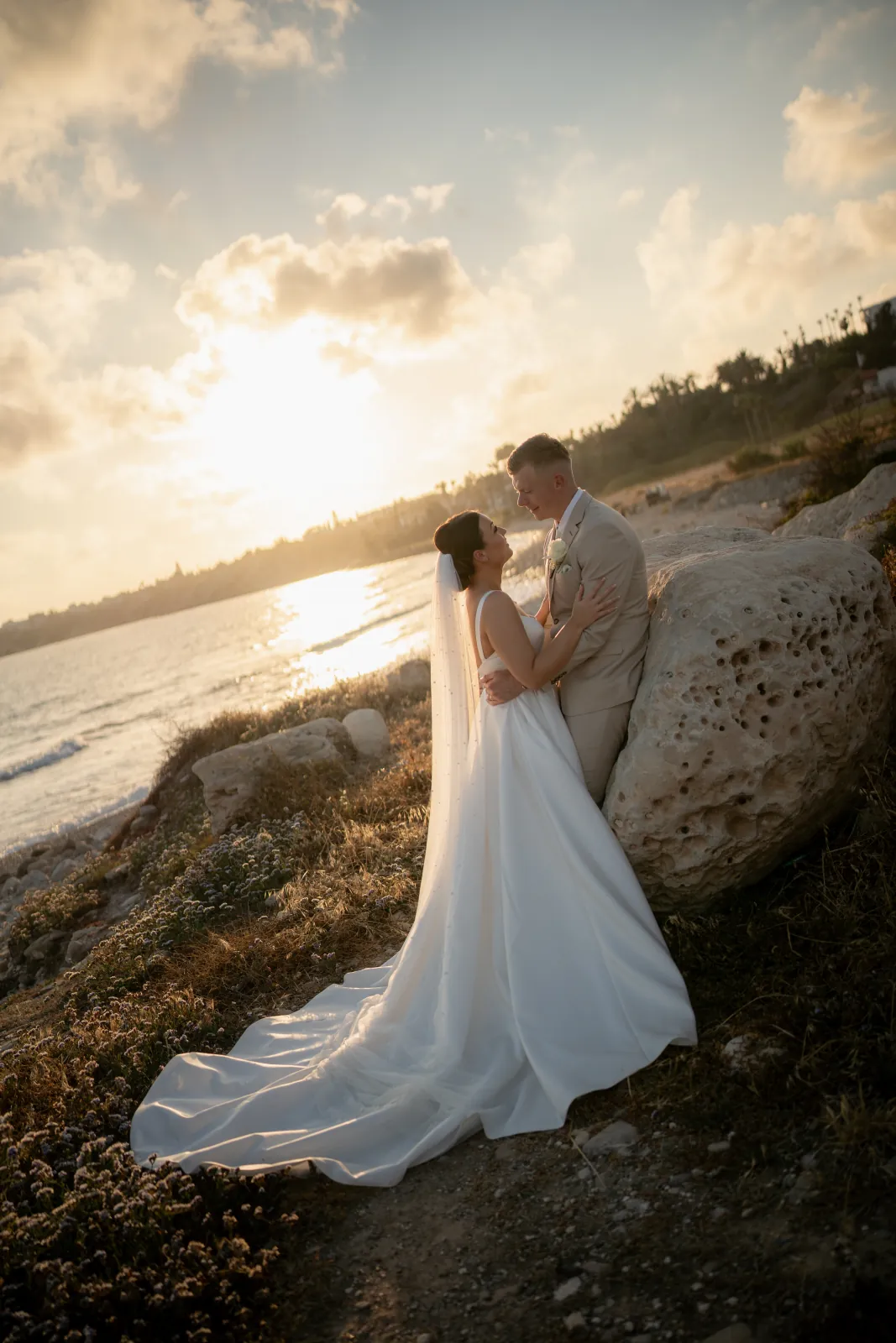 Bride and groom at golden hour on the rocks as the sun sets over the sea at Coral Residences, Paphos, Cyprus